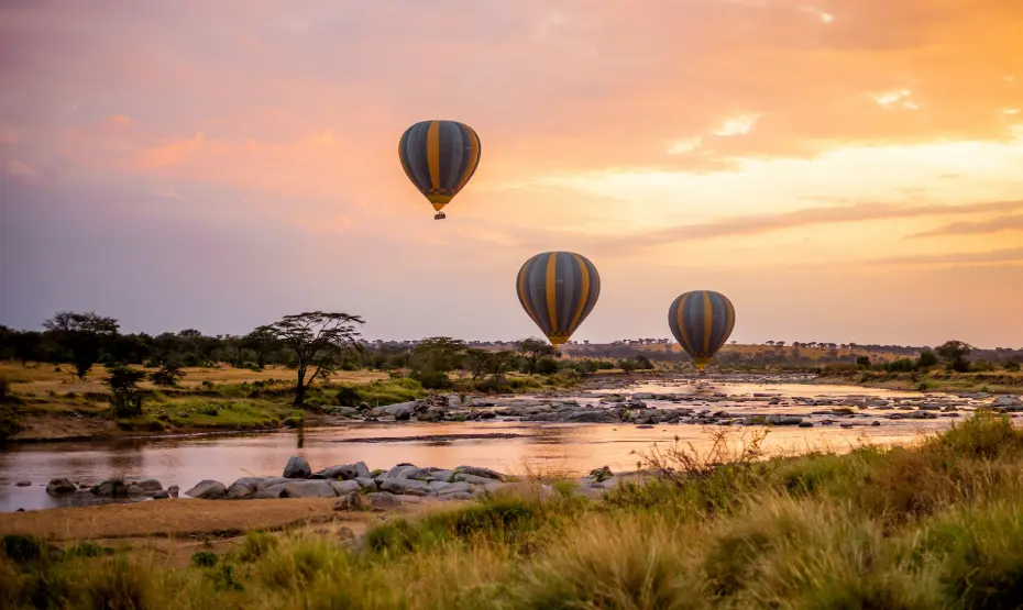 Things to do in Tanzania 2025 - Classic wildlife Safaris three hot air balloons flying over a river in Serengeti National Park